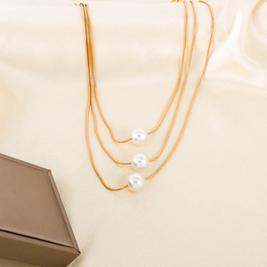 Elegant multi-layered gold snake chain necklace with three round white pearls on silk background
