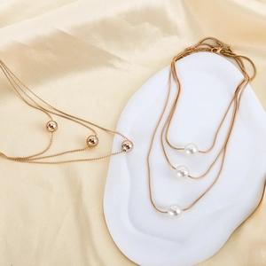 Detail of elegant gold-tone layered necklaces with metallic beads and white pearls on silk