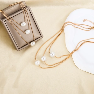 Elegant gold multi-layered snake chain necklace with white pearls on satin background