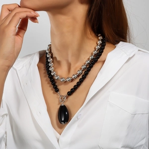 Detail of double-layer beaded necklace featuring a large black oval pendant and toggle clasp
