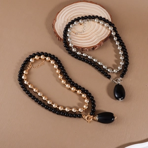 Close-up of double-layered beaded necklace with black water drop pendant and metal beads