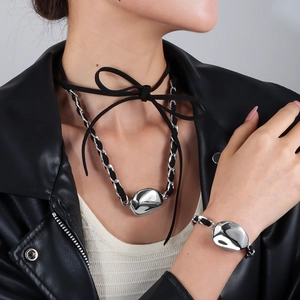 Dettaglio di ciondoli argentati su collana in velluto nero e bracciale coordinato