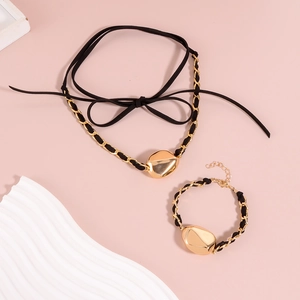 Dettaglio di set choker e bracciale in velluto nero con perle dorate irregolari