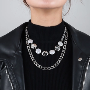 Detail einer zweilagigen silbernen Gliederkette mit rundem Anhänger auf schwarzem Pulli
