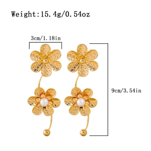 Detailansicht langer goldener Blumenohrringe mit weißen Perlen und gehämmerter Metallstruktur