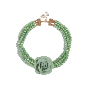 Detailweergave van de drielaagse groene parelketting met grote stoffen bloem in het midden