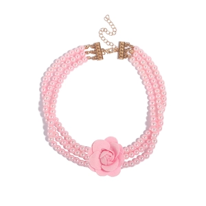 Detail van de drielaagse roze parelketting met een grote stoffen bloem als centraal accent