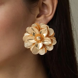 Nahaufnahme eines großen goldenen Metall-Blumenohrrings mit Schichten an einem Model