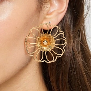 Schicke, übergroße goldene hohle Blumenohrringe mit filigranem Strahlenblüten-Design am Model
