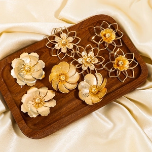 Goldene überdimensionale Blumenohrringe mit strukturierten Blüten in Schmucktablett