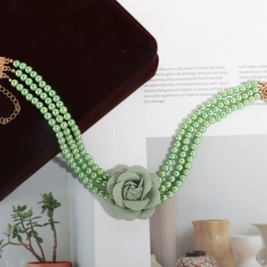 Macro-detail van meerlaagse groene parelketting met grote stoffen rozenhanger