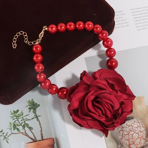 Detail van een choker met grote rode stoffen roos en glanzende donkerrode imitatieparels