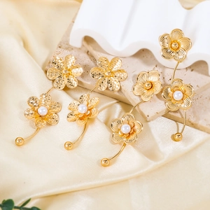 Detailansicht der goldenen Blumenohrringe mit weißen Perlen auf Satinhintergrund