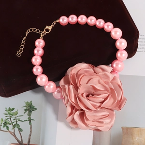Detail van roze parelketting met grote stoffen roos en gouden metalen sluiting