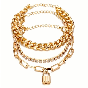 Dettaglio del set di braccialetti dorati con catena cubana, ciondolo a lucchetto e zirconi