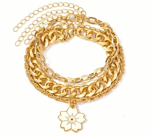 Dettaglio di bracciali a strati placcati oro con ciondolo a fiore di ciliegio smaltato