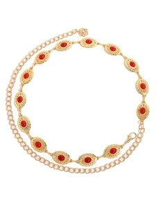 Detail of golden metal waist chain with red oval gemstones and flower pendant