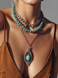 Close-up of layered bohemian turquoise and silver leaf pendant necklace on model