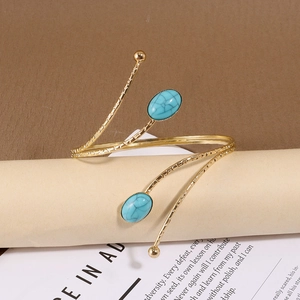Vue détaillée d'un bracelet de bras bohème doré avec deux turquoises sur un livre