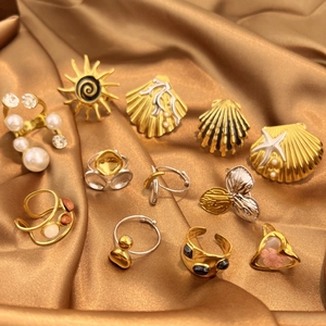 Minimalistisches Set aus Edelstahlringen mit Sonnenblumen und Perlen auf goldenem Satin