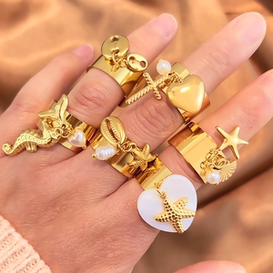 Gold stainless steel rings with starfish shell pendants and pearls on a satin background