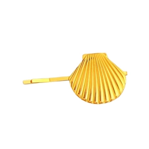Golden seashell hair clip with textured radial stripes on a clean white background