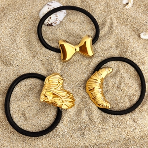 Set de chouchous avec breloques dorées cœur nœud et lune sur un fond de plage de sable