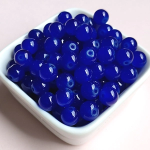 Close-up of 8mm deep blue glass beads with drill holes in a white ceramic bowl