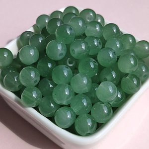 Close-up of translucent green 8mm glass beads in a bowl for DIY jewelry making