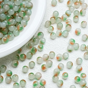 Macro view of 8mm translucent jelly glass beads with green and orange floral patterns