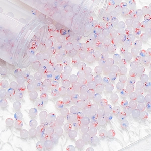 Macro detail of 8mm ink-gold frosted glass beads with red and blue splash textures