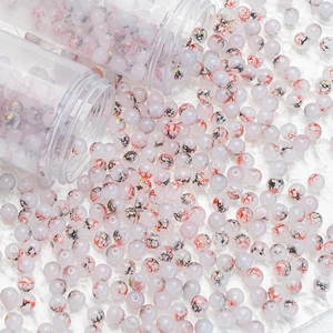 Detailed macro view of 8mm and 10mm glass beads with gold splash and ink texture