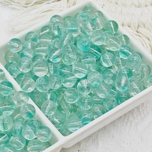Gros plan de perles de verre translucides vert clair dans un plateau de tri