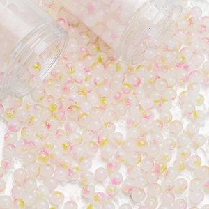 Macro shot of 8mm translucent ink-wash glass beads with pink and green floral patterns