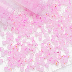 Macro detail of pink and gold ink-splattered glass beads for DIY jewelry making