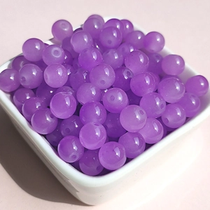 Macro shot of purple translucent 8mm glass beads in a white bowl for DIY jewelry