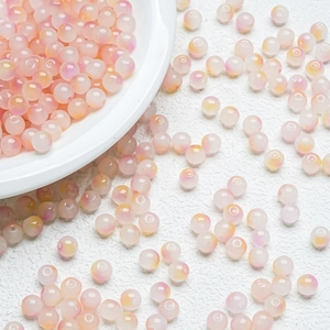 Close-up of gradient pastel round glass beads on white ceramic plate for DIY jewelry making