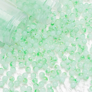 Macro detail of mint green glass beads with gold foil and ink spots for DIY jewelry