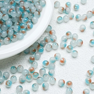 Macro detail of 8mm marbled glass beads with ink splatter patterns for DIY jewelry
