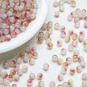 Macro detail of 8mm jelly glass beads with pink and green floral pattern for DIY jewelry