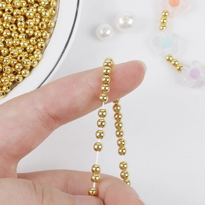 Close-up of threading small 14K gold plated beads for DIY handmade jewelry crafts