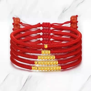Detail of red braided cord bracelets with adjustable strings and gold spacer beads