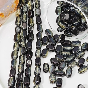 Macro shot of 6x10mm black glass beads with iridescent glitter texture for DIY jewelry