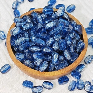 Macro shot of 6x10mm deep blue glass beads with cat eye texture in a wooden bowl
