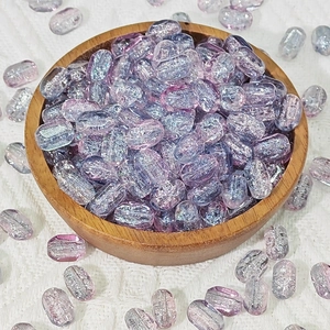 Macro detail of 6x10mm purple and blue gradient glass beads with glitter in a wooden tray