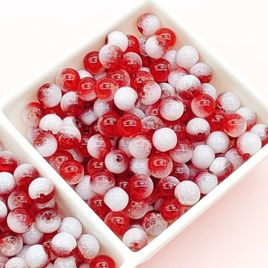 Close-up of red and white crackle glass beads in a white organizer tray for DIY crafts