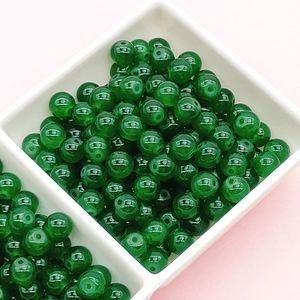 Detail of 8/10mm dark green crackle glass beads in a white tray for DIY jewelry making