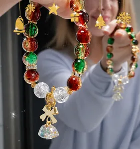 Detailed shot of Christmas handmade bracelet with red green glass beads and gold bell charms