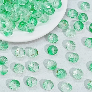 Dettaglio di perle sfaccettate in vetro verde sfumato in un piatto di ceramica per gioielli