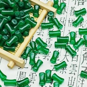 Close-up of a green bone-shaped glass bead on a bamboo tray with a vintage background